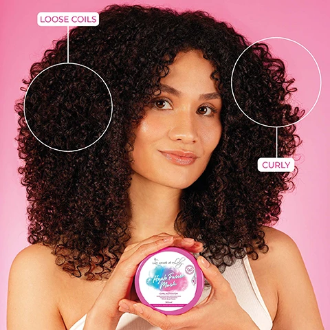 Image 1 - A woman with large, voluminous curly hair smiles while holding a pink jar labeled Hazel Texture Mask Curl Activator in front of a pink background, with text on the image identifying sections of her hair as Loose Coils and Curly.
Image 2 - Image shows a pink background with a hair care product jar labeled Hyalur Fusion Mask at the center, with the text A REAL CURL ACTIVATOR above it and 87% BOUNCIER CURLS below.
Image 3 - A hand is holding a round container of Hyda Fusion Mask with a gradient color design, against a pink background, and includes text arrows pointing to features described as hydrates in depth, activates curl bounce, and even curls.
Image 4 - A pink and white jar labeled Hyla Fusion Mask sits on a reflective surface surrounded by purple flowers, with highlighted text describing ingredients: Marshmallow Extract smoothes the fiber and adds slip, Hyaluronic Acid rehydrates in depth, and Chickpea Extract proteins and amino acids rich for a bouncy effect.